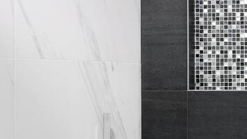 Um banheiro moderno com parede de mármore, área de chuveiro revestida em azulejos e painel de controle de chuveiro cromado.