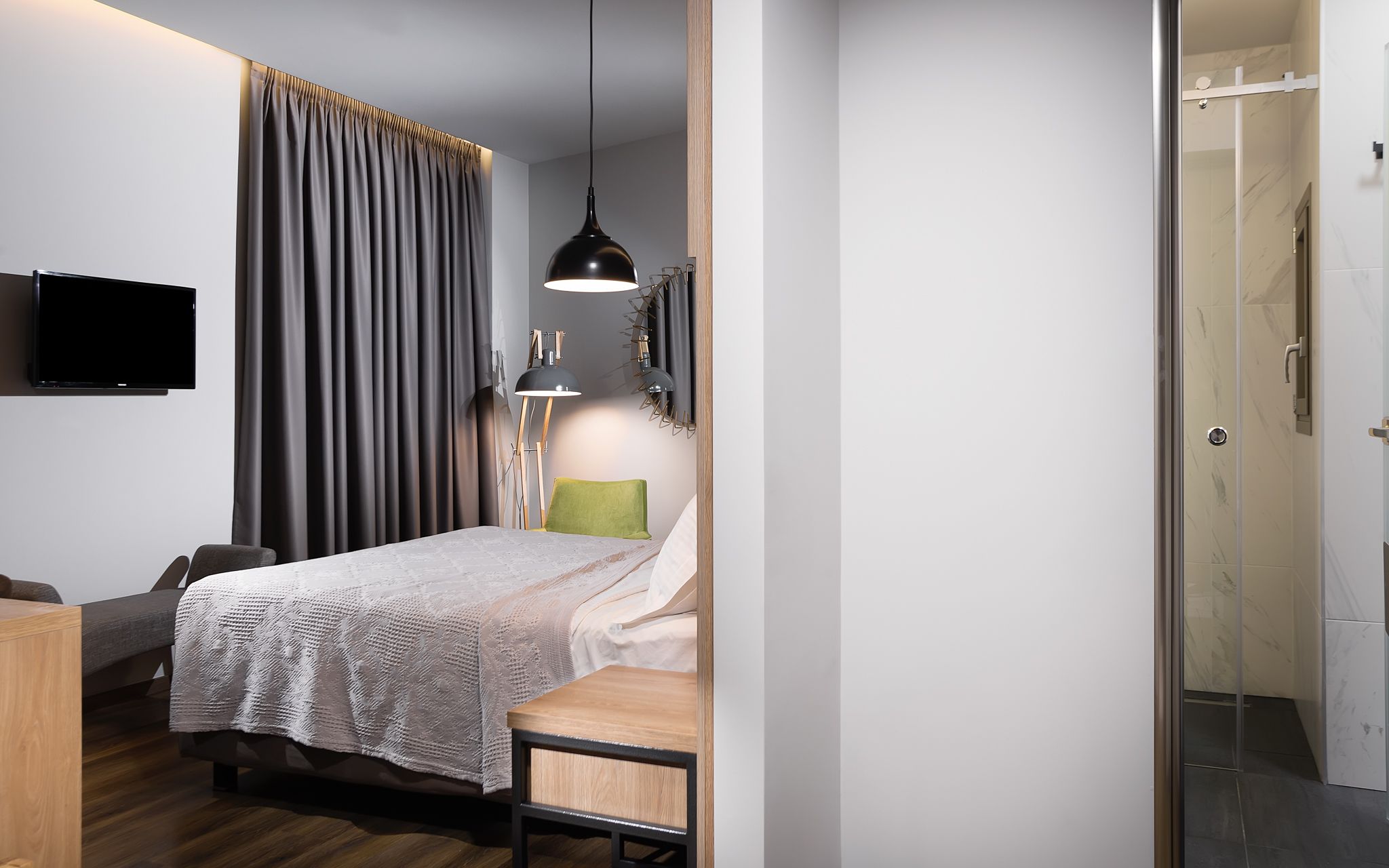 Une chambre moderne comprenant un lit, un bureau, une chaise, un téléviseur et un espace douche.
