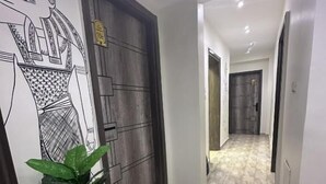 A hallway with a tiled floor, a potted plant, and a door with a geometric pattern. - Giza Pyramids Inn (Giza)