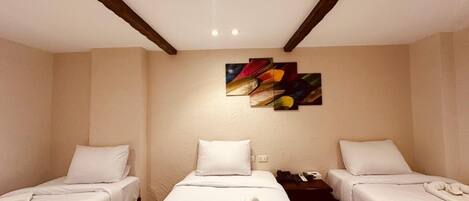 A hotel room with two single beds, a nightstand, a painting on the wall, and a ceiling light.