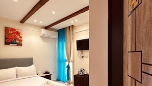A hotel room with a large bed, a flat-screen TV mounted on the wall, and a wooden door with a room number sign. - Giza Pyramids Inn (Giza)