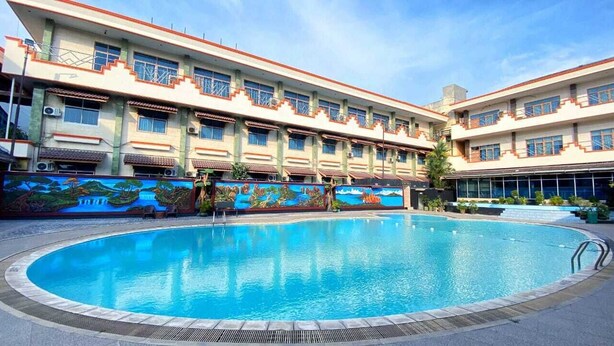 A swimming pool surrounded by a building with a mural. - Soeltan Luxe Hotel (Bandar Lampung)