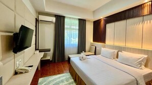 A hotel room with a bed, a TV, a desk, and a window with curtains. - Soeltan Luxe Hotel (Bandar Lampung)