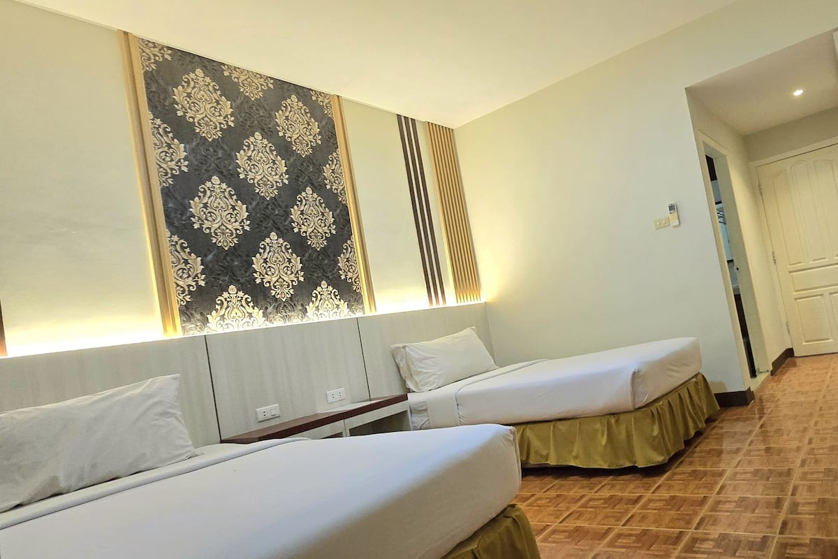A hotel room with two beds, a desk with a telephone, a television, and a door leading to a bathroom.
