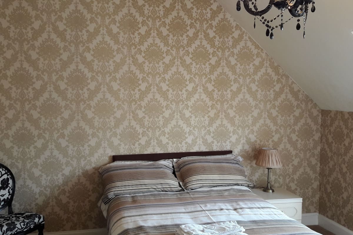 Un dormitorio con cama, una silla, una lámpara y una araña.