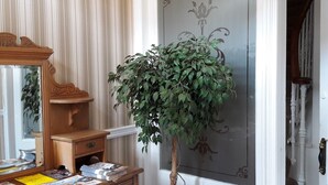 Un aparador de madera con espejo, periódicos, una planta en maceta y una puerta con panel decorativo.