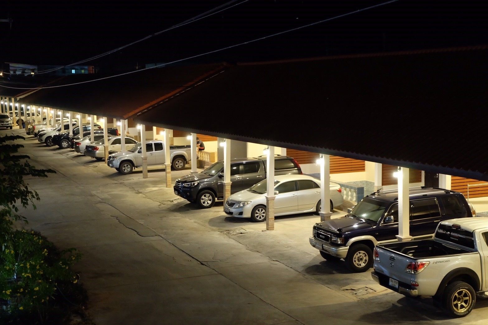 A parking lot with multiple cars and a covered area.