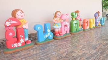 Alphabet letters and child figurines adorn the floor in a playful outdoor setting.