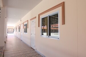 Un pasillo con puertas y ventanas que conduce a un espacio abierto con un edificio al fondo.