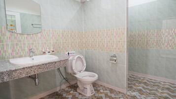A bathroom with a sink, toilet, and mirror. The walls are tiled with a pattern, and the floor has a herringbone design.