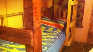 Una habitación pequeña y acogedora con una litera, una escalera de madera y cortinas estampadas.