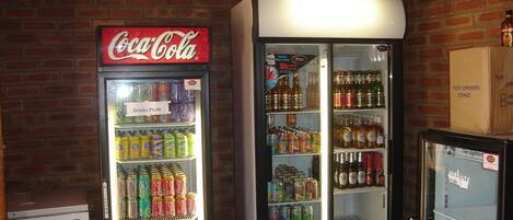 Dos máquinas expendedoras de bebidas, una marca Coca-Cola y otra con una variedad de opciones, frente a un muro de ladrillo.