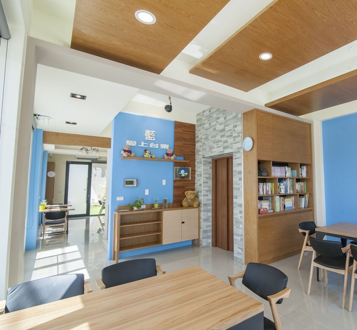 A modern reception area with a blue wall, wooden shelves with books, and a wooden reception desk.