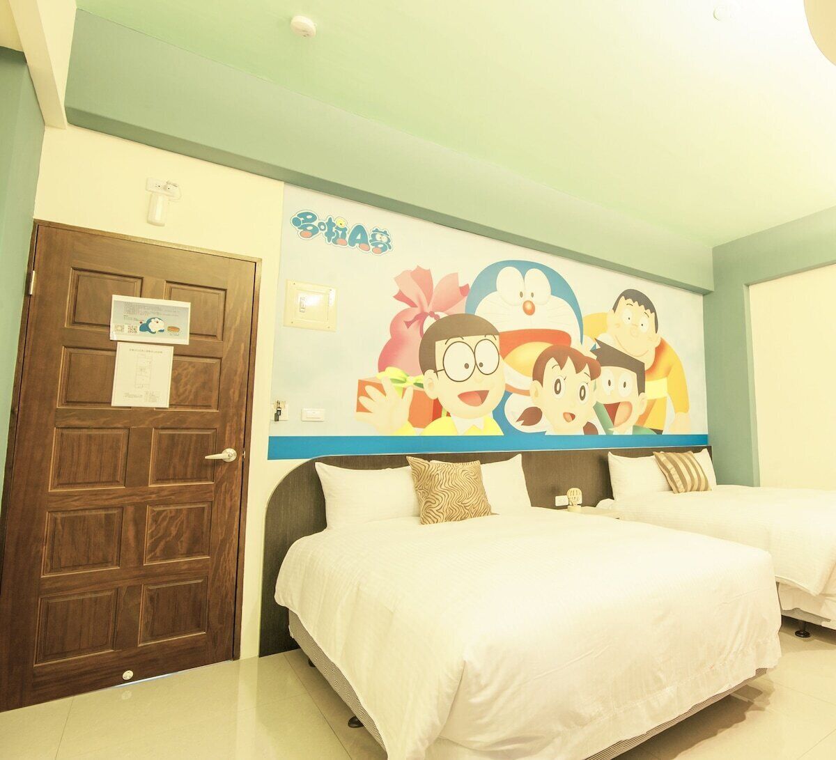 A hotel room with a large bed, two pillows, a wooden door, and a wall mural.