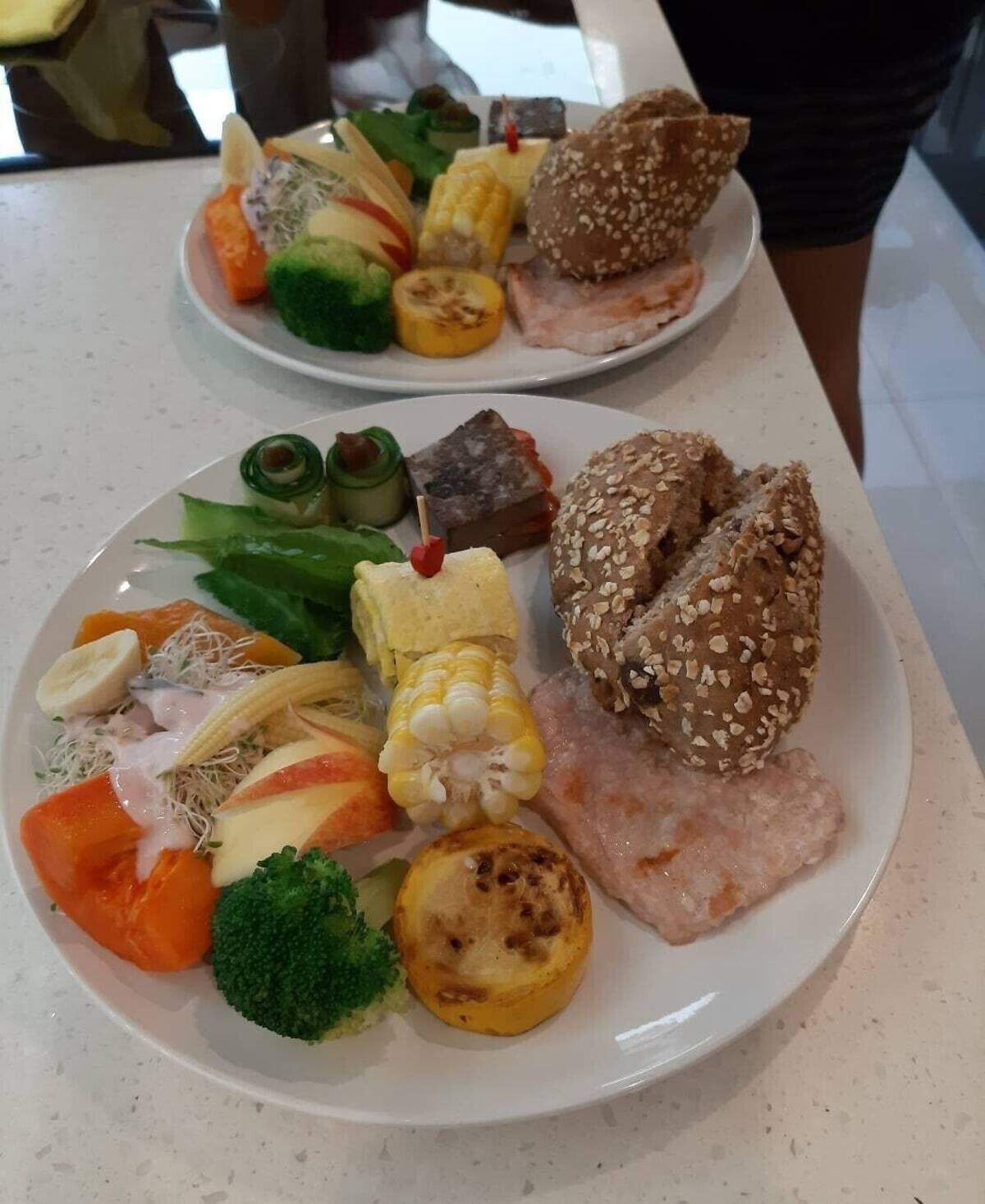 Dos platos de comida con diferentes verduras y un trozo de carne.