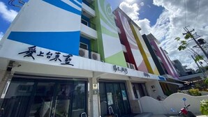 A hotel with a modern facade, multiple floors, and a prominent sign with a blue and white design. - TT Blue B&B (Taitung)