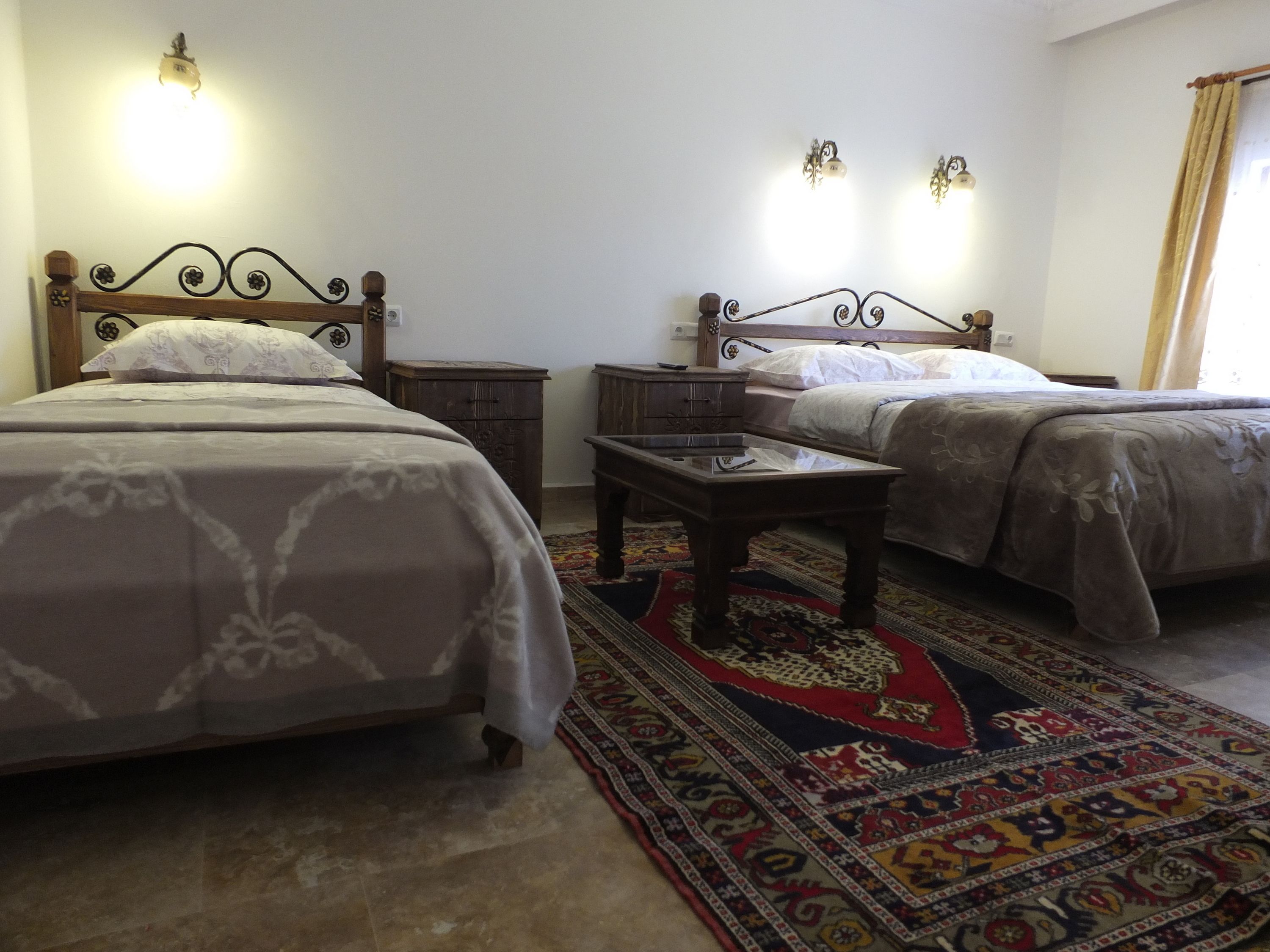 A hotel room with two beds, a small table, and a decorative rug.