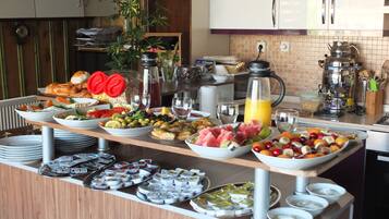 A buffet with various food items and beverages, a coffee maker, and a plant in the background.