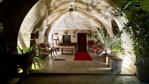 A cozy, stone-walled room with a reception desk, seating area, and potted plants.