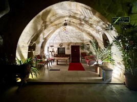 Una habitación acogedora con paredes de piedra, un mostrador de recepción, zona de estar y plantas en macetas.