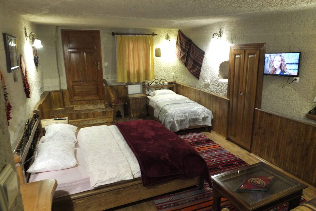 Ein Schlafzimmer mit zwei Betten, einer Holztreppe, einem Fernseher und einem kleinen Tisch.