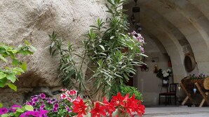 A stone archway leading to a terrace with potted plants and flowers.