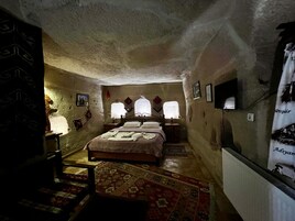 Una habitación acogedora y rústica con una cama grande, una mesita de noche de madera, una pequeña mesa y una alfombra estampada.