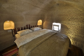 A cozy bedroom with a large bed, patterned bedding, and two wall-mounted lamps. - Anatolia Cave Hotel Pansion (Nevsehir)
