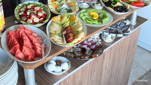 A breakfast buffet with various fruits, vegetables, and eggs.