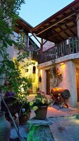 Un patio con plantas en macetas, un banco de madera y un edificio con balcón.