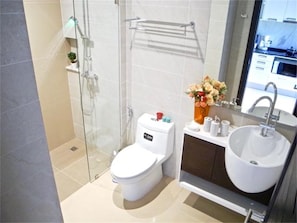 A modern bathroom with a glass-enclosed shower, a white toilet, a vanity with a sink, and a mirror.