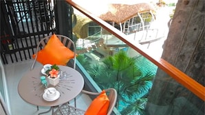 Uma varanda com mesa e cadeiras, uma pequena planta e vista para um edifício com telhado vermelho.