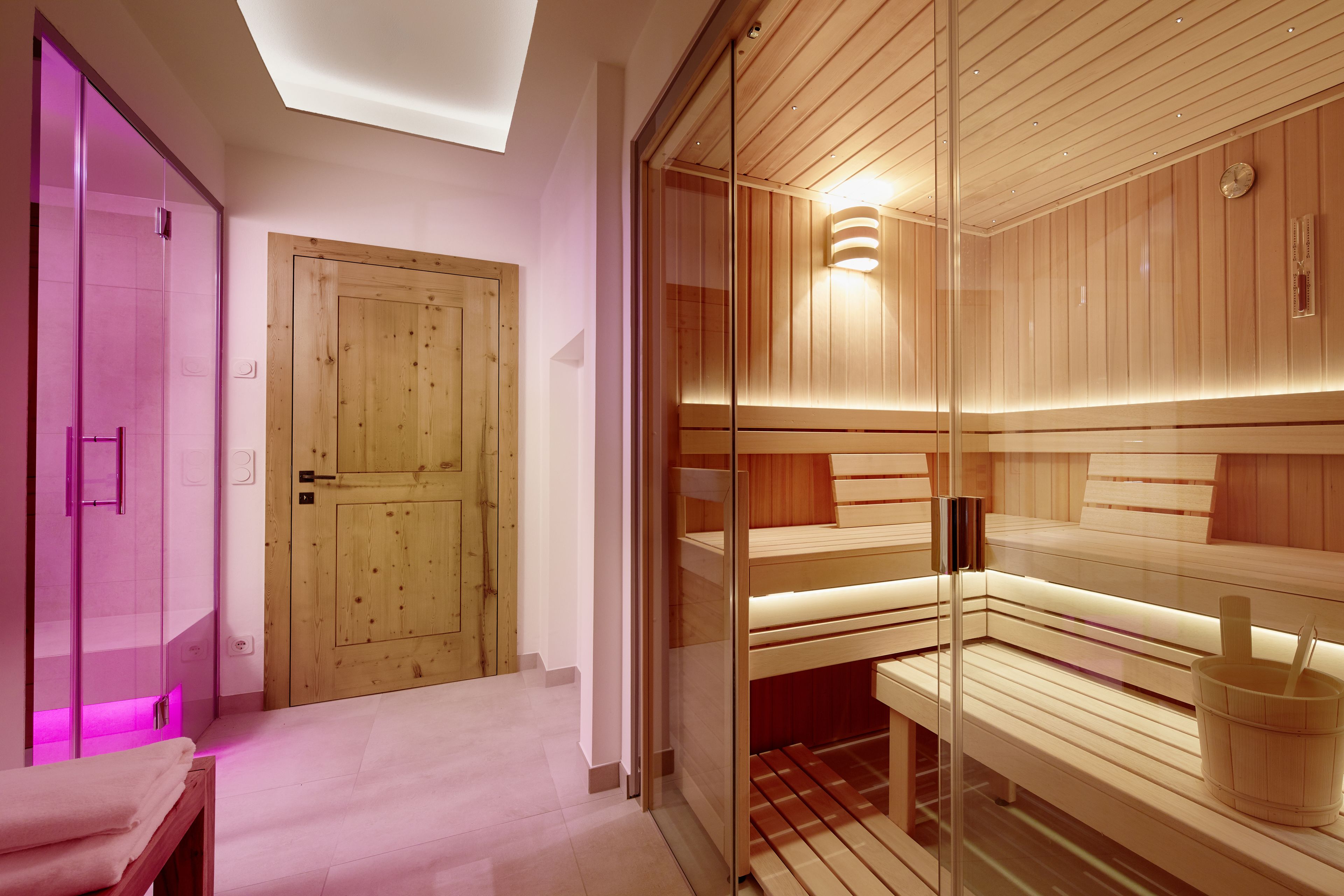 Un sauna moderno con bancos de madera y un panel de vidrio.