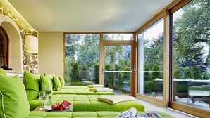 A bright room with a green sofa, a table with a plate of fruit, and a newspaper. - Tennerhof Luxury Chalets (Kitzbuhel)