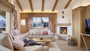 Una sala de estar acogedora con chimenea, vigas de madera, un sofá y un televisor.