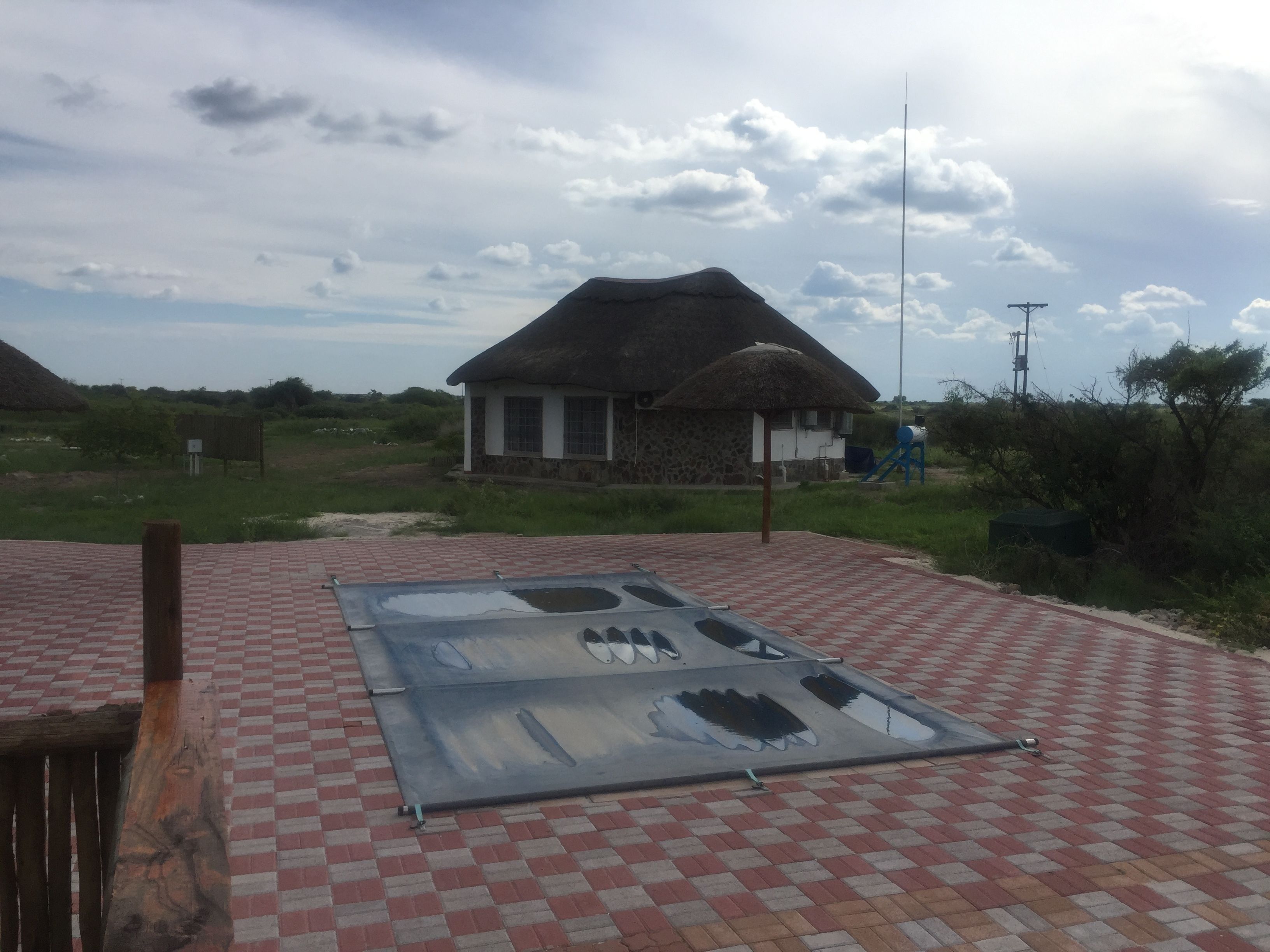 A thatched-roof house with a checkered floor and a metal structure on the roof.