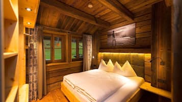 Relax in this serene bedroom with a large bed and unique headboard, featuring a flat-screen TV and a large window with a view of the surrounding landscape.