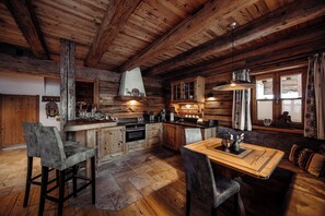 A rustic wooden interior with a kitchen, dining area, and seating.