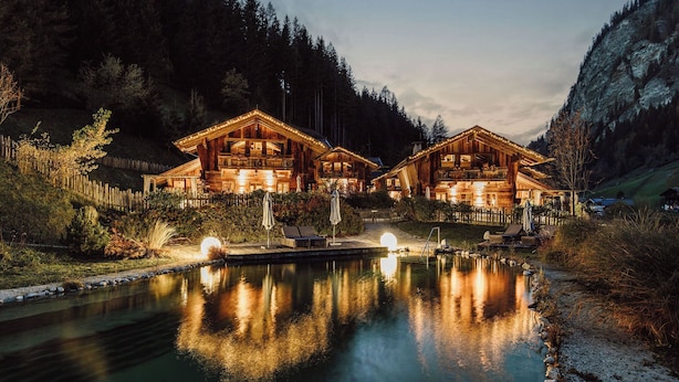 A lodge with a pool, surrounded by forested hills. - Chaletdorf Auszeit (Huettschlag)