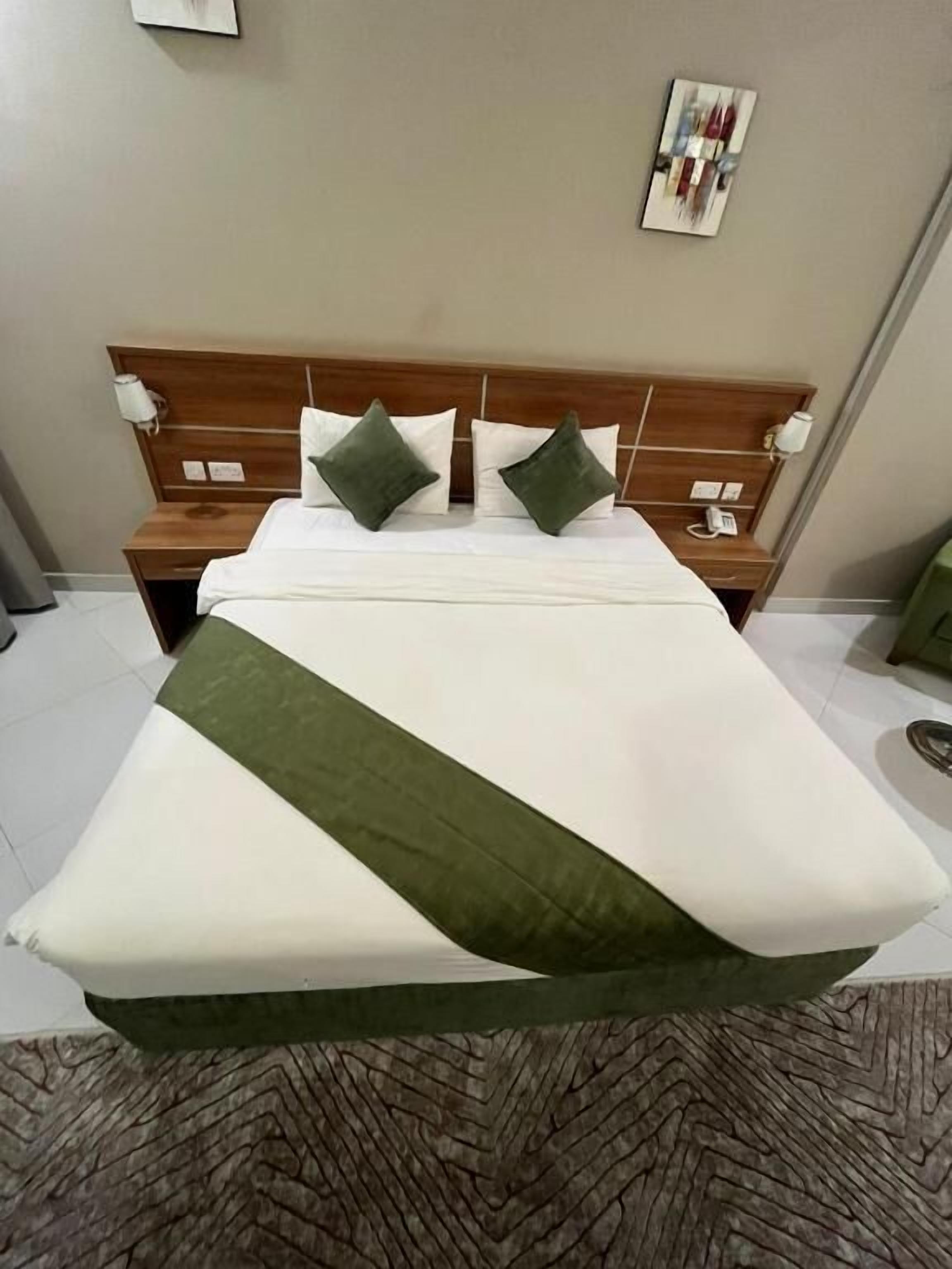A hotel room with a bed, two bedside tables, and a wall-mounted artwork.