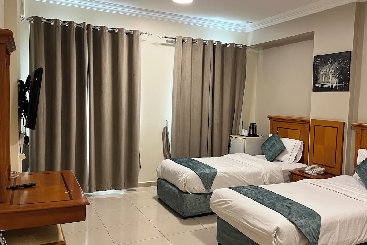 A hotel room with two beds, a desk, a TV, and a coffee maker.