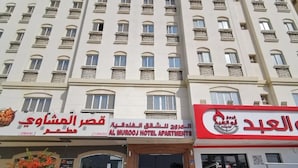A multi-story hotel with balconies, a restaurant, and a sign for Al-Murooj Hotel Apartments. - Al Murooj Hotel Apartments (Muscat)