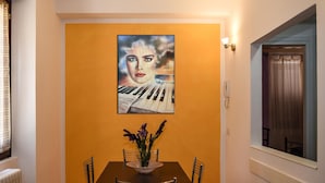 A dining area with a table, chairs, a vase with flowers, and a painting on the wall. - B&B Villa Sophie (Assisi)