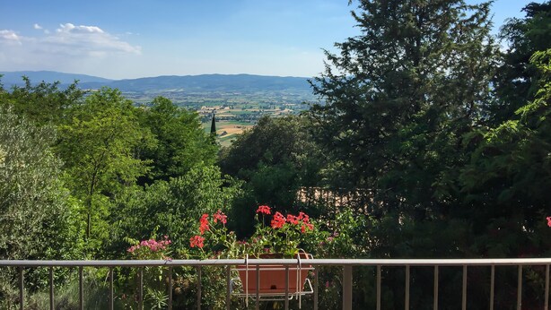 A scenic view from a balcony with a railing, overlooking a valley with distant mountains and a clear sky. - B&B Villa Sophie (Assisi)