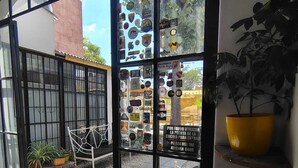 A glass door entrance with various stickers and a sign in Spanish, a wooden bench, and potted plants inside. - Mora Hostel (Mendoza)