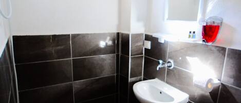 A bathroom with a white sink, a toilet, and a shower. There is a window with blue trim and a mirror above the sink.