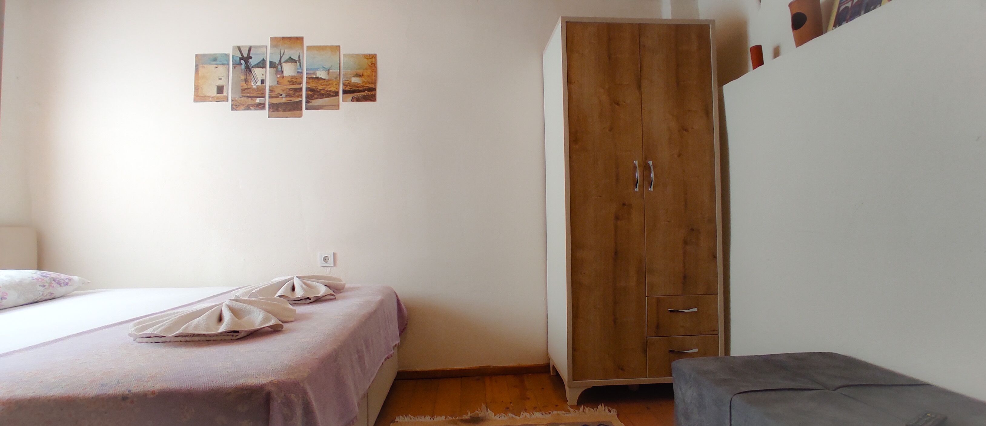 Ein Schlafzimmer mit einem Bett, einem Kleiderschrank und einer Wand mit mehreren Fotos.