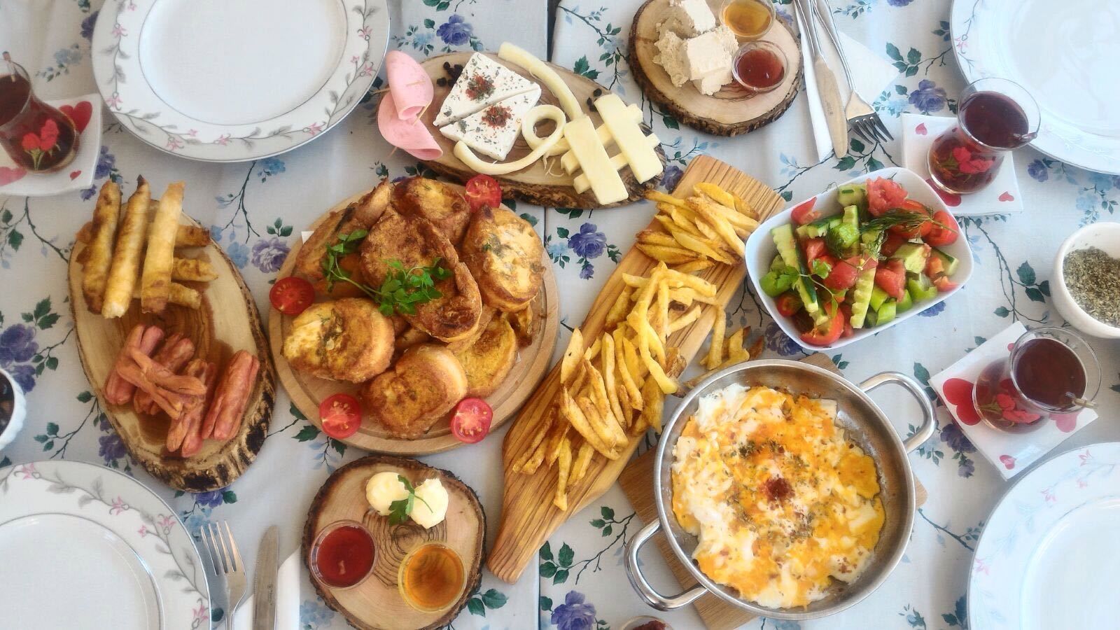 Une table dressée avec divers plats, notamment des plats frits, une salade et un assortiment de fromages.