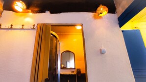 Ein Durchgang mit Spiegel, einer Leuchte darüber und einem an der Wand befestigten Regal mit Dekoration.
