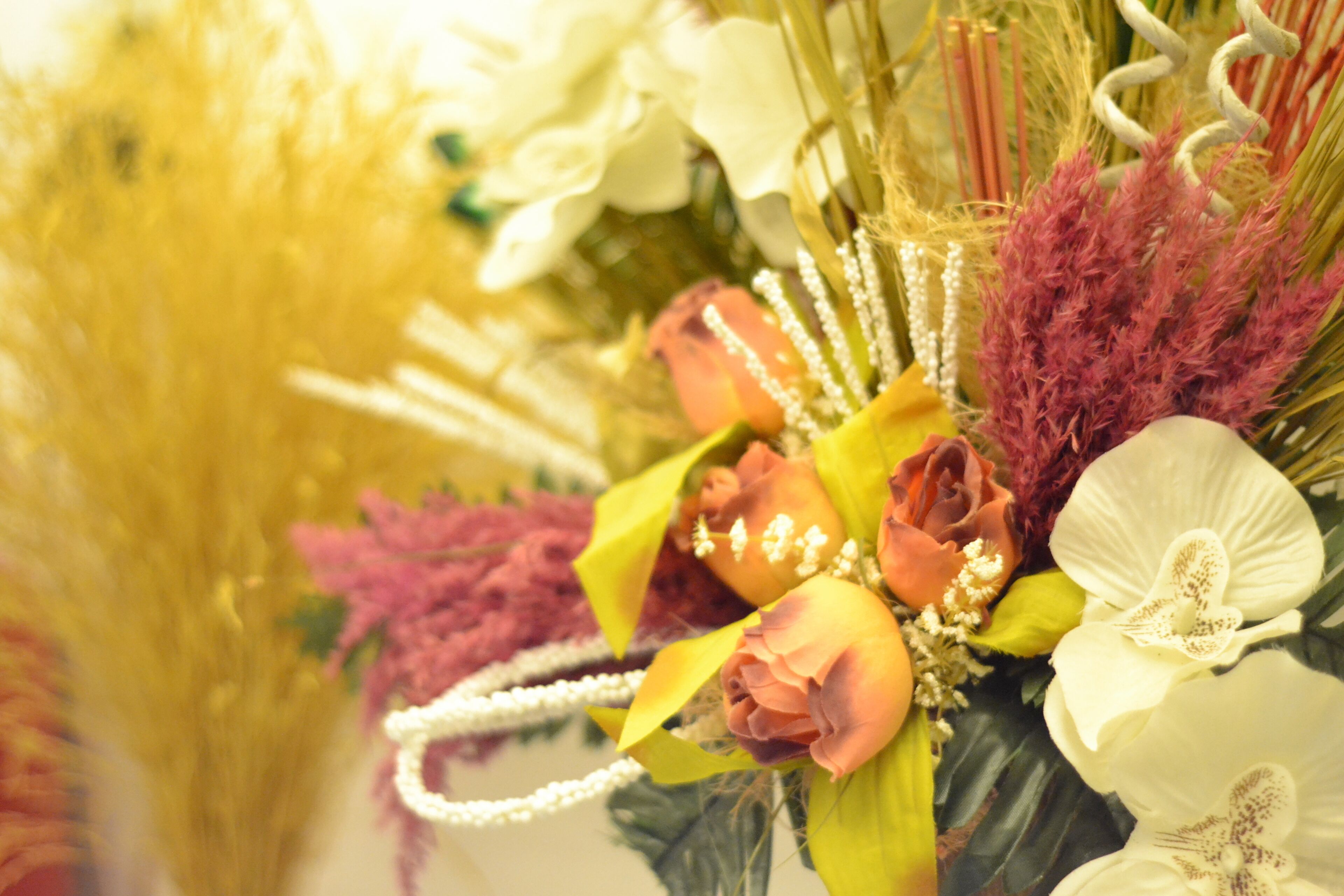 A bouquet of flowers with various types including roses, white orchids, and yellow and purple foliage.